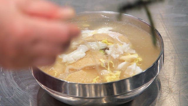 Putting fried tofu on hot fish cake soup