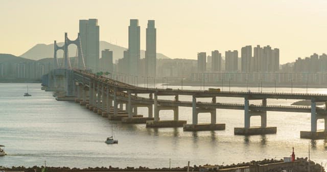 Evening view of a bustling port city Busan with tall skyscrapers and Gwangan Bridge