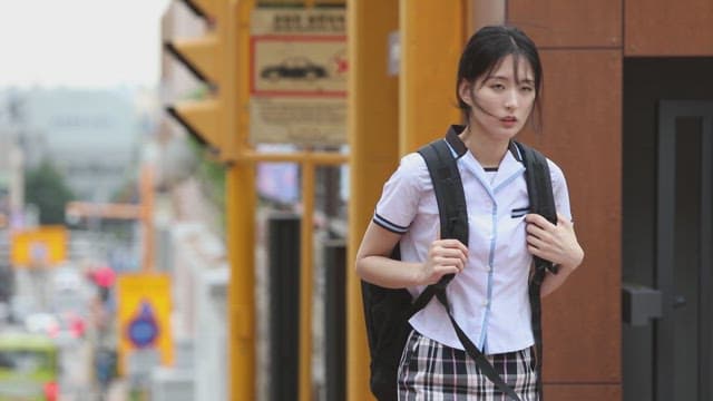 Student walking along a street with signs in the background