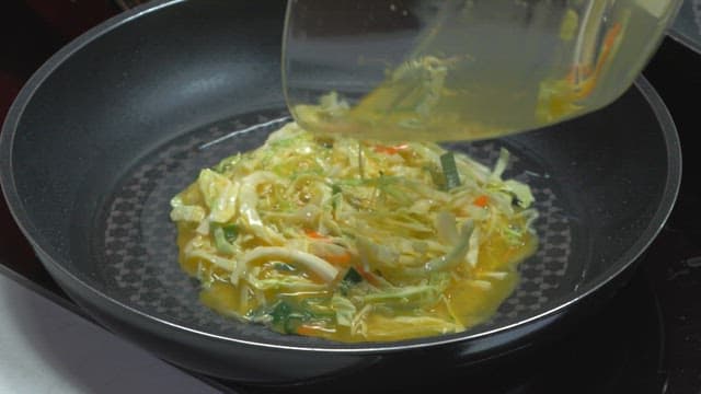 Placing eggs and vegetables together on an oiled frying pan