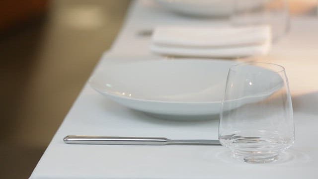 A neatly set dining table with plates and glasses
