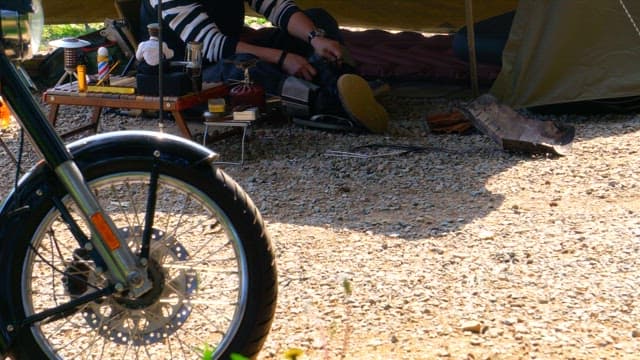 Man tying his shoes at a campsite on a sunny day