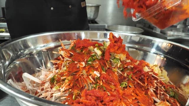Chef Mixing Red Pepper Powder and Vegetables in the Kitchen