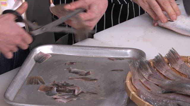 Preparing fish for cooking by removing fins and scaling