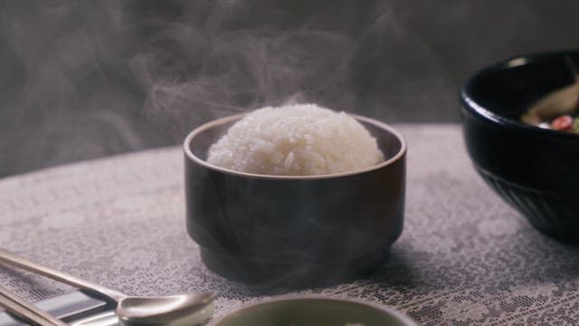 Steaming Rice Served in a Black Bowl