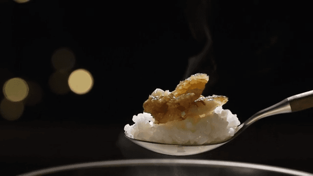 Spoonful of rice topped with a piece of well-cooked grilled corvina