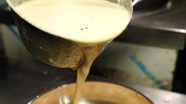 Soybean soup poured over noodles in a metal bowl