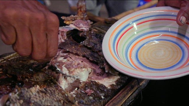 Grilled giant trevally being prepared with a fork