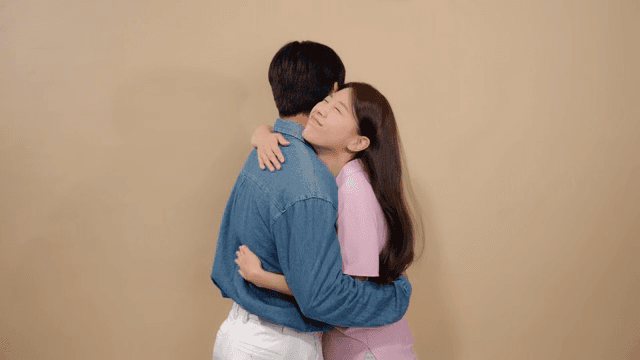 Couple embracing each other affectionately in a neutral-colored room.