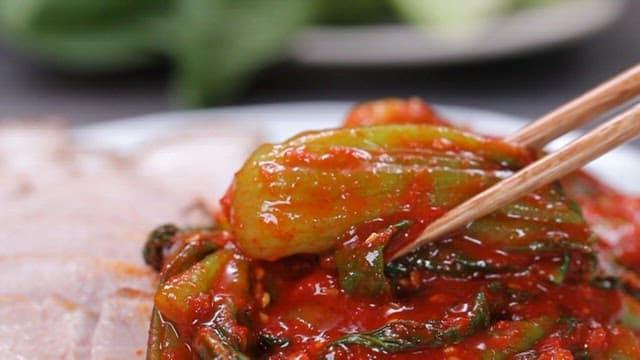Bok choy kimchi being picked up with chopsticks