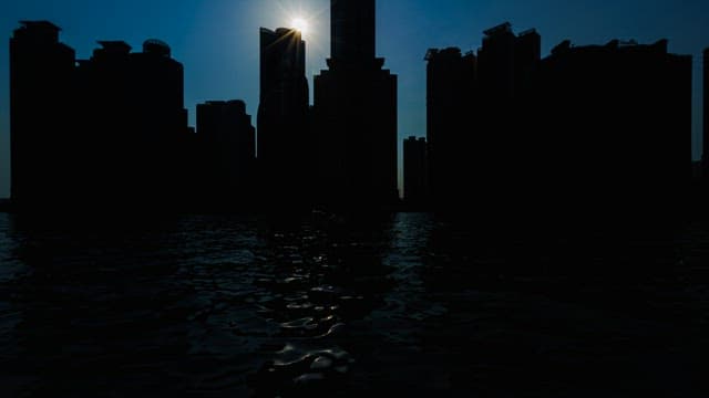 Silhouettes of Buildings in Riverside City Against the Sun