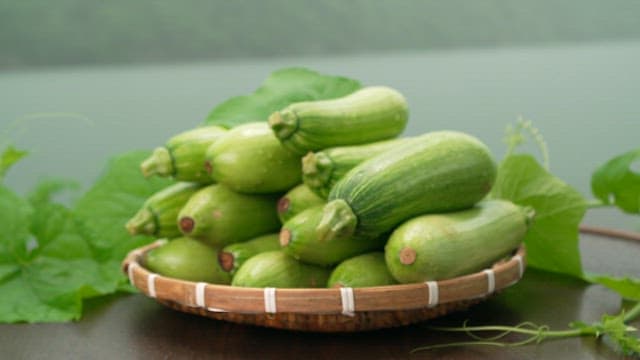 Fresh green zucchini stacked in a basket on a table