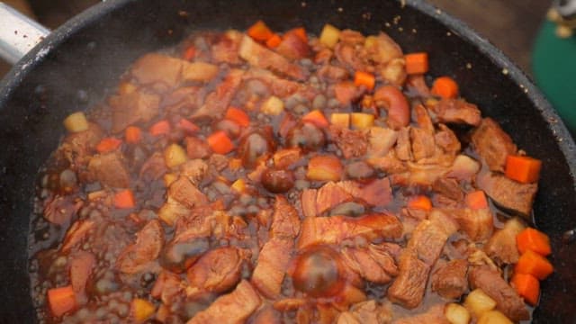 Braised pork shank simmering in a pan