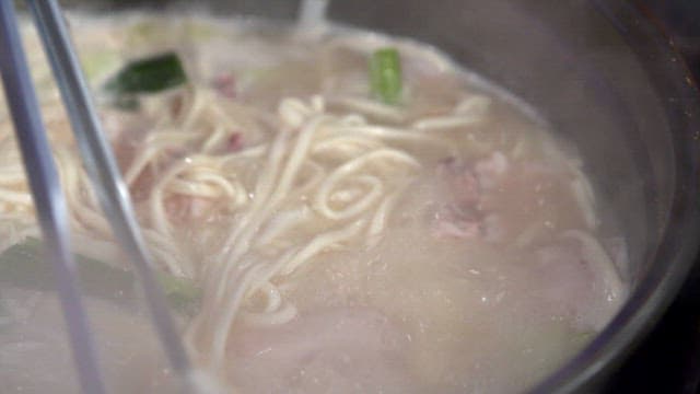 Noodle soup with chicken boiling in a pot