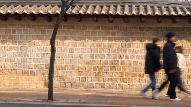 People walking past a traditional wall