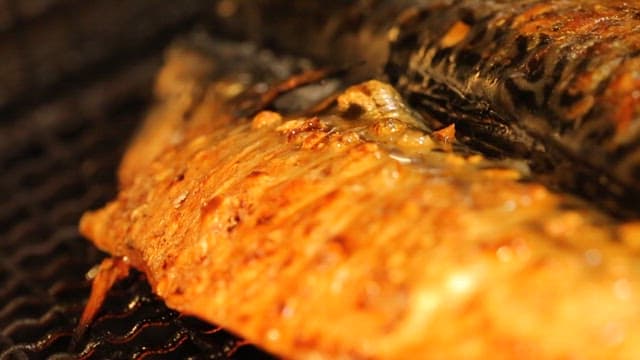 Grilled mackerel sizzling on a grill
