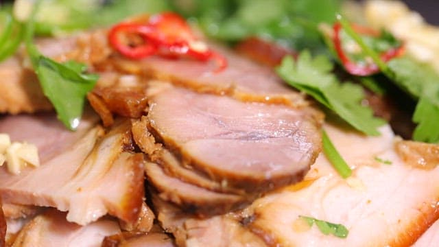 Five-spice pork garnished with herbs and peppers