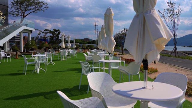 Outdoor terrace with empty white chairs and tables on a cloudy day