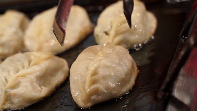 Crispy fried dumplings being cooked on a griddle