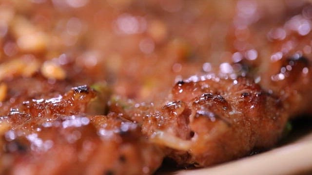 Grilled tteokgalbi being cut with chopsticks