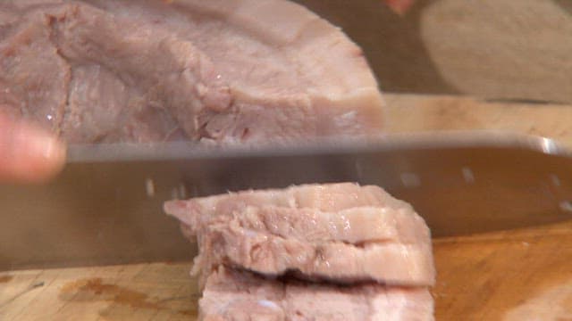 Slicing boiled pork on a cutting board