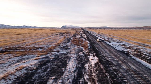 Car driving on a snowy road in open fields