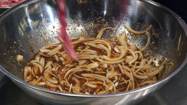 Mixing meat and onions in a soy sauce marinade