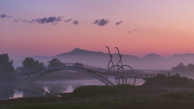 Serene bridge over a misty river at sunset