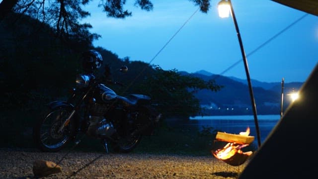 Campsite lit by lanterns and campfires under the blue evening sky