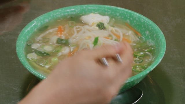 Chopsticks of noodles with vegetables and warm broth