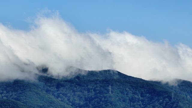 Clouds covering a lush green mountain