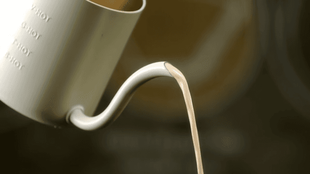Pouring milk into a white coffee pot