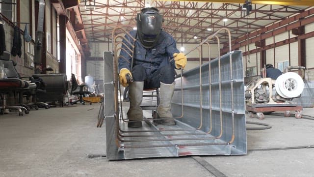 Worker welding metal beams in a factory
