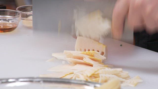 Cutting boiled bamboo shoots with a knife on a cutting board