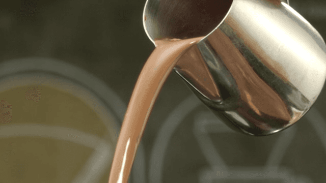 Chocolate syrup poured from a metal pot
