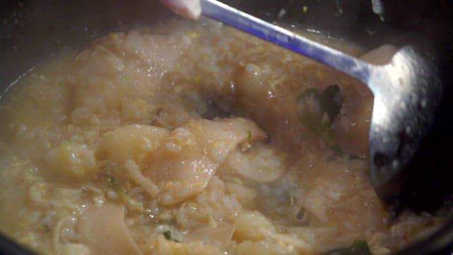 Noodle soup with chicken porridge stirred with a ladle