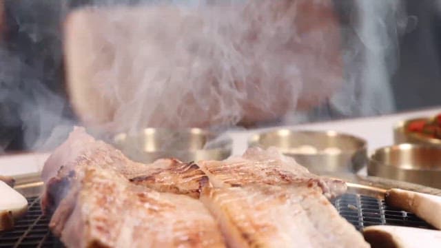 Pork belly sizzling on a grill