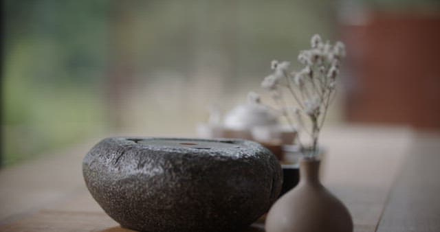 Hand Setting the Glass Kettle on Rock Surface