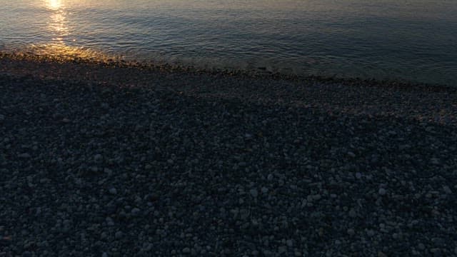 Serene sunrise over a calm pebbly beach