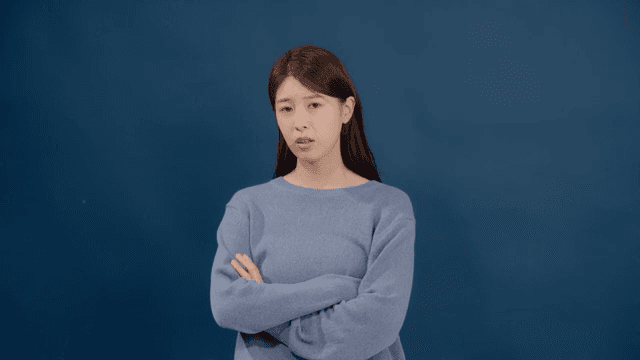 Long-haired woman with arms crossed and a disgruntled expression
