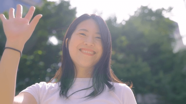 Woman smiling and waving outdoors