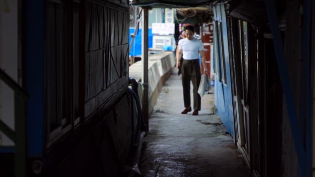 Man walking down a narrow alley while talking on the phone