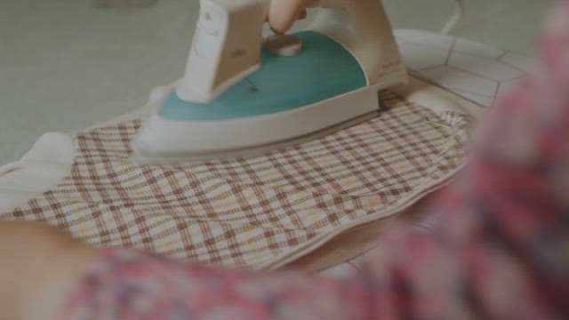 Ironing a checkered fabric on an ironing board in a cozy indoor setting.