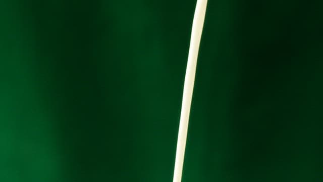 White milk and brown coffee poured against a green screen