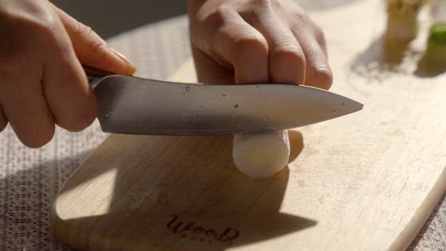 Hand Slicing onions on a wooden cutting board