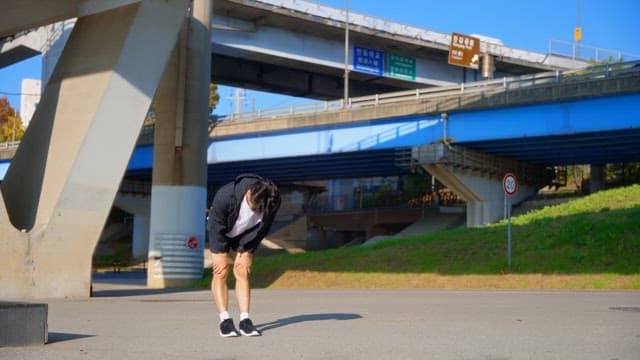 Man exercising under a highway bridge