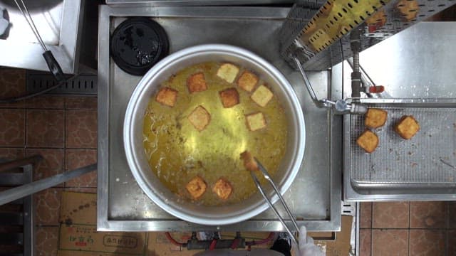 Frying bread in hot oil in a pan in a restaurant kitchen