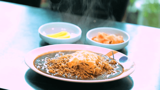 Cheese blackbean ramyeon with side dishes on a table
