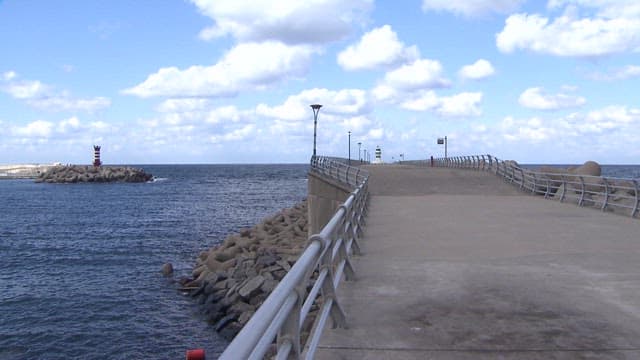 Pier Stretching into the Sea with Red Lighthouse