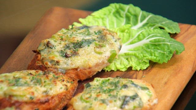 Crispy and appetizing baguette topped with green onions on a wooden cutting board